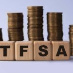 TFSA (Tax free savings account) acronym on wooden cubes on the background of stacks of coins