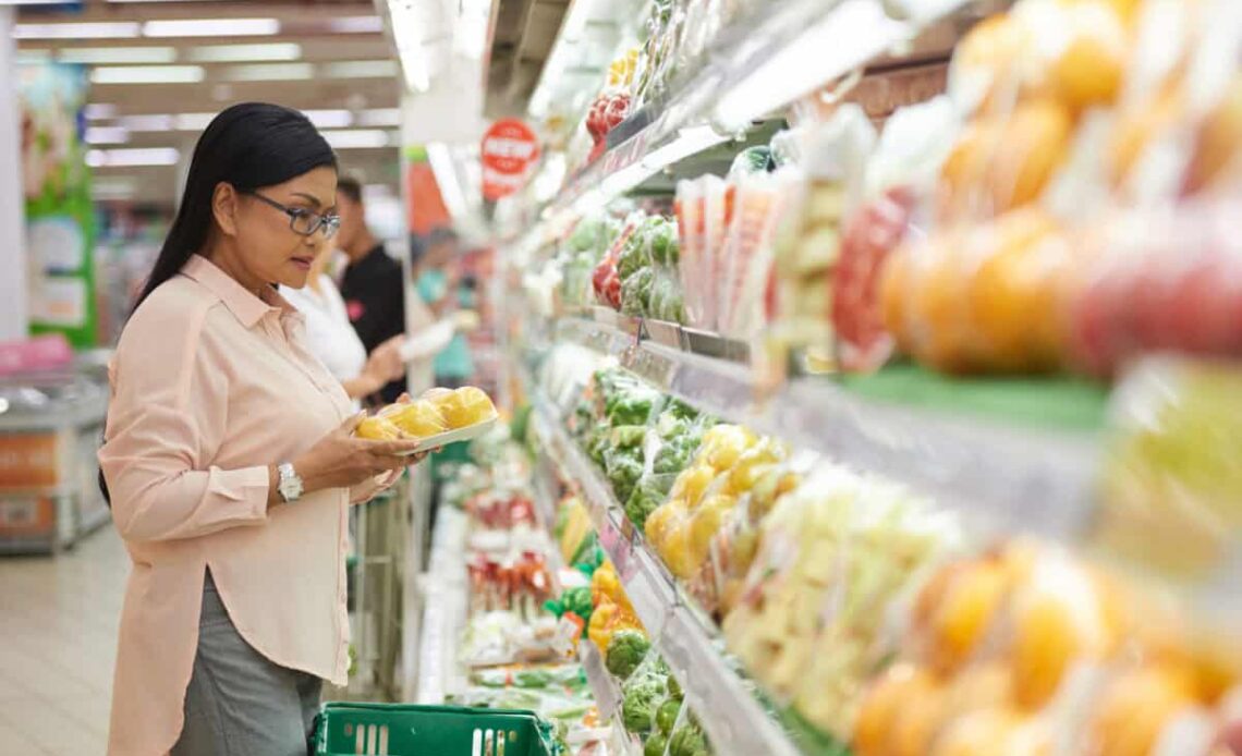 shopper chooses vegetables at grocery store
