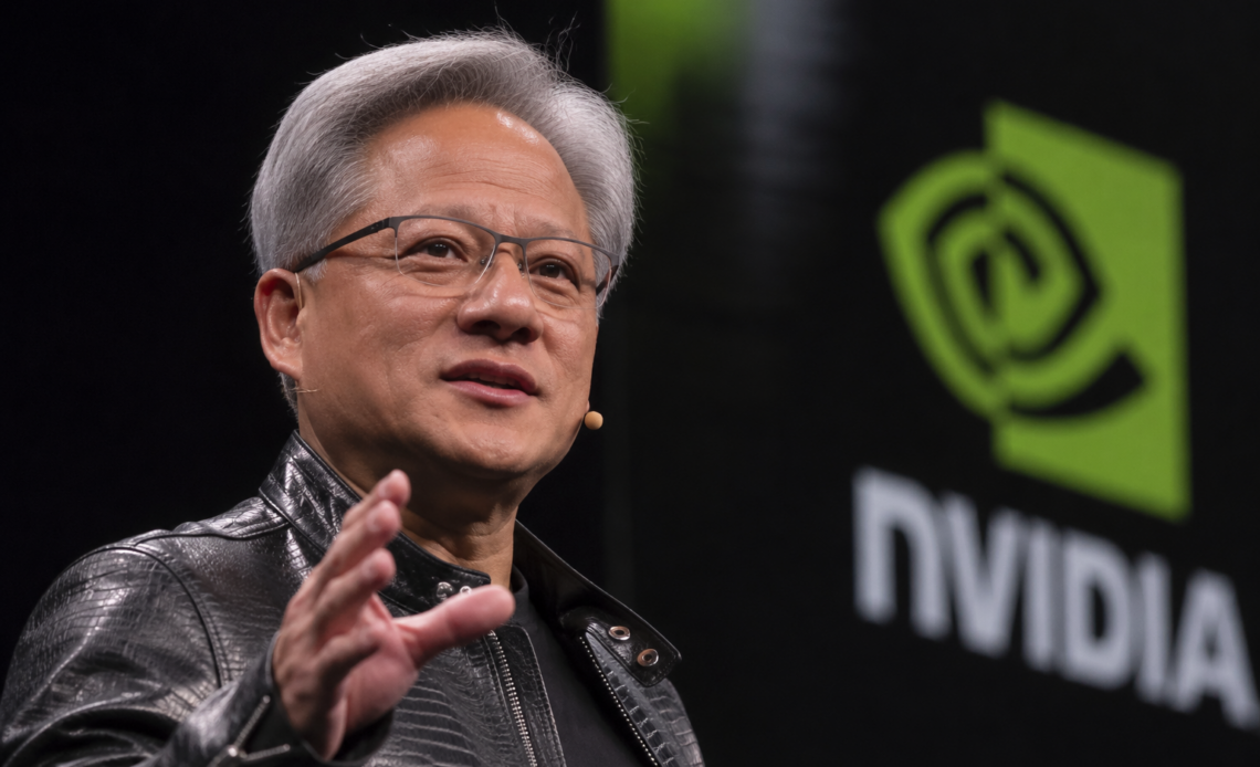 Jensen Huang speaks on stage beside a large Nvidia logo during a technology event.