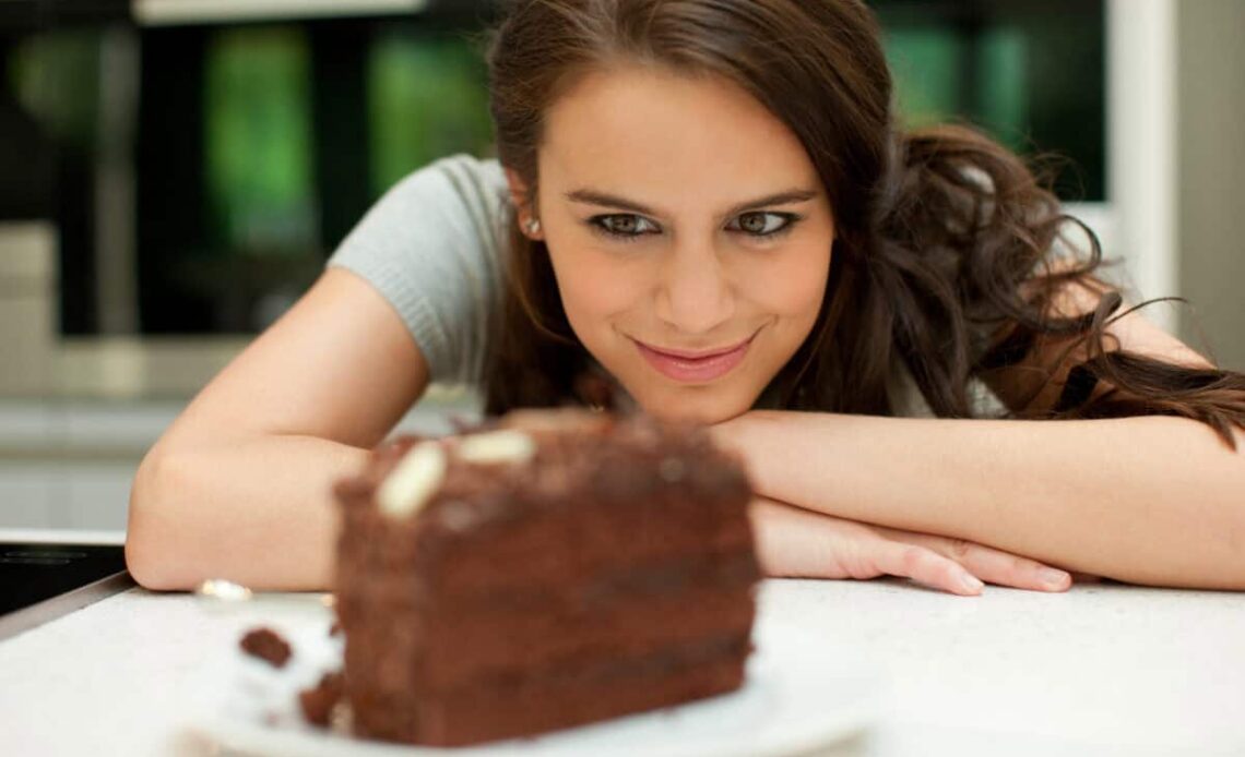 woman stares at chocolate layer cake